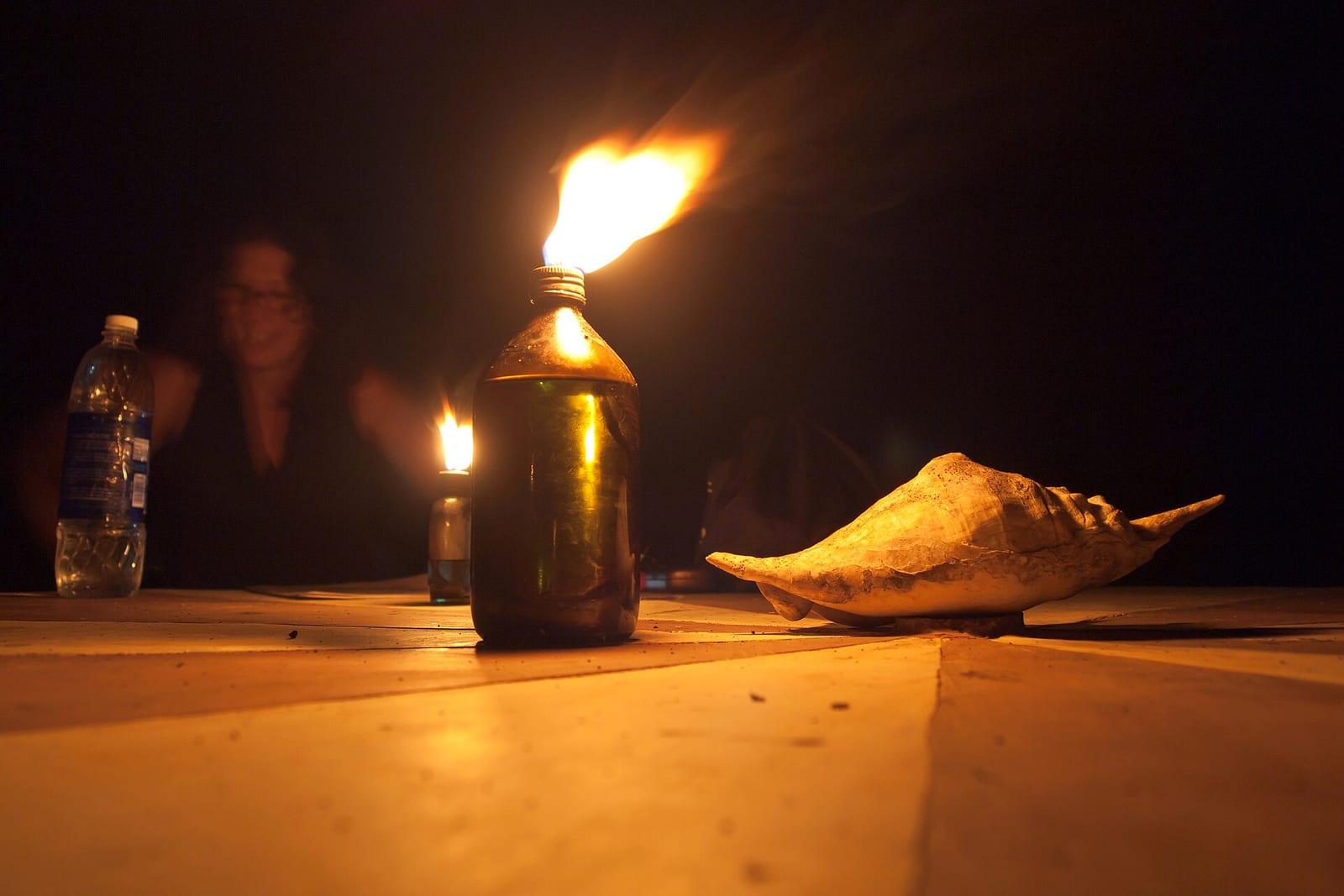 A candle flame glowing in the dark during a night ceremony.